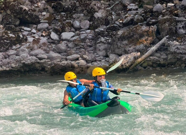 Two people kayaking on a river surrounded by rocks. 1