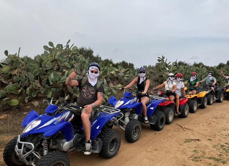 A group of people riding ATVs on a dirt path surrounded by cacti. 1