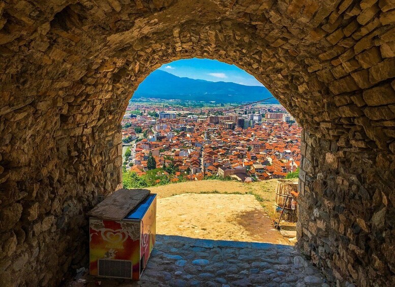 An archway leading to a cityscape with a mountain in the background. 3