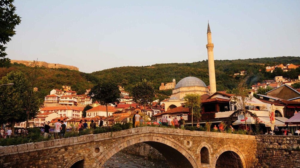 A historic town with a prominent minaret, a stone bridge, and a dome-shaped building. 5