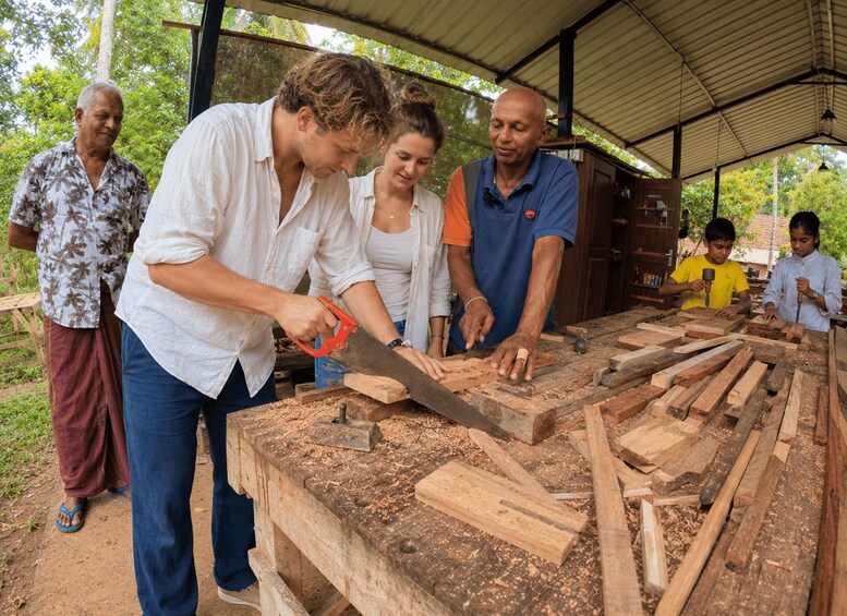 A group of people engaged in woodworking, with a man sawing wood and others assisting. 3