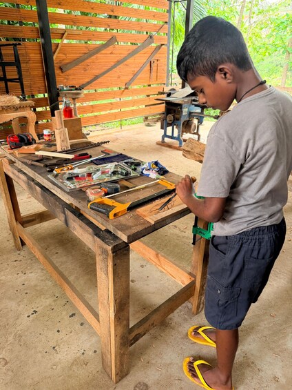 A person working at a wooden workbench with tools and materials. 4