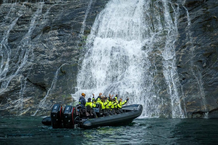 A group of people in a boat near a waterfall. 1