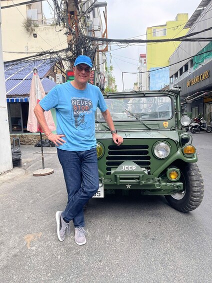 A man standing next to a green military jeep on a city street. 2
