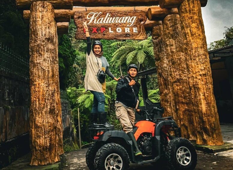 Ein Holzschild mit der Aufschrift 'Kaliuang Explore', zwei Personen auf einem Quad und eine tropische Landschaft im Hintergrund. 4