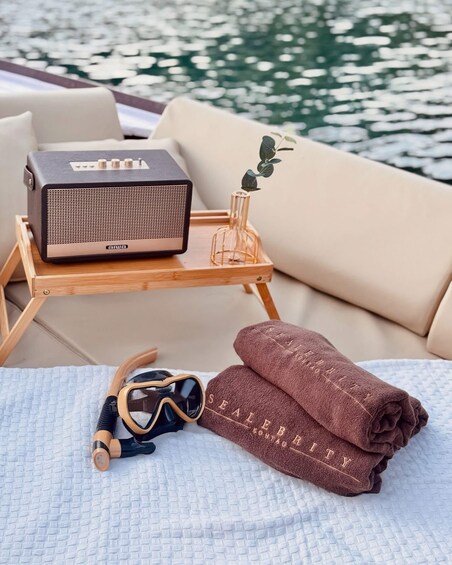 A beachside setting with a portable speaker, sunglasses, and towels on a lounge chair. 5