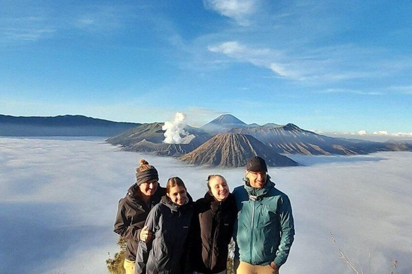 Un grupo de personas de pie sobre un paisaje nevado con un volcán al fondo. 1