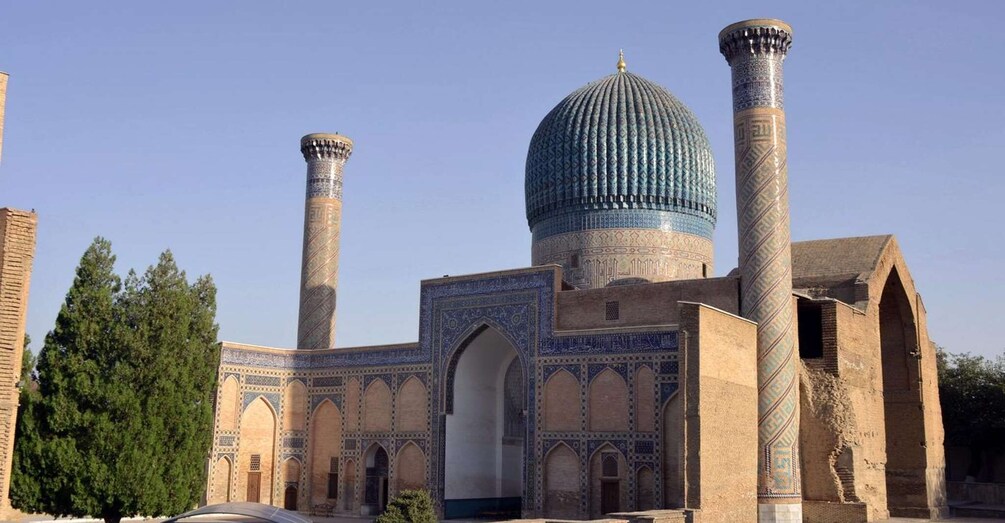A historic building with a large dome and two tall minarets, featuring intricate tile work and arched doorways. 1