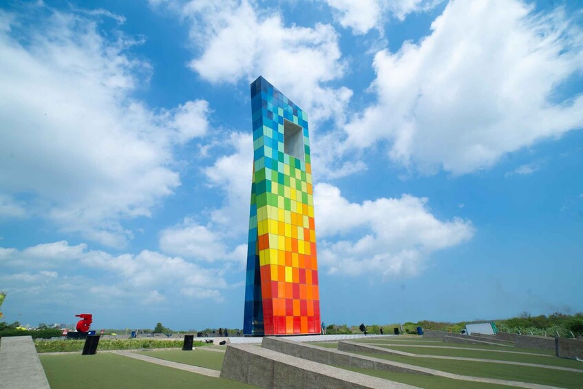 A tall, colorful tower with a checkered pattern against a blue sky with clouds. 5