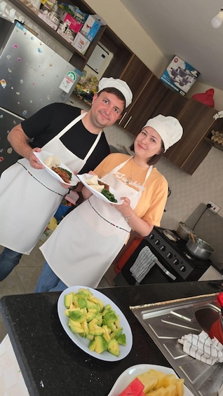 Two people in a kitchen holding plates of food. 4