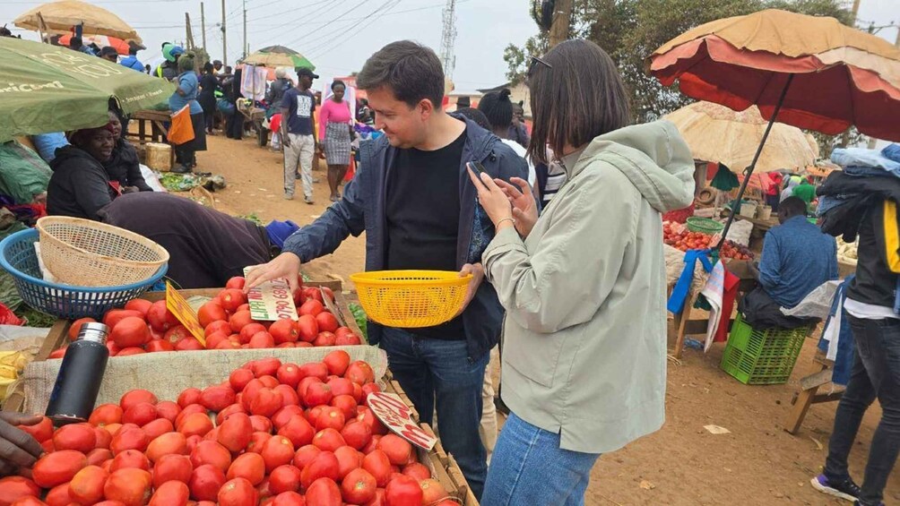 A bustling outdoor market with people buying and selling goods, including a vendor selling tomatoes. 2