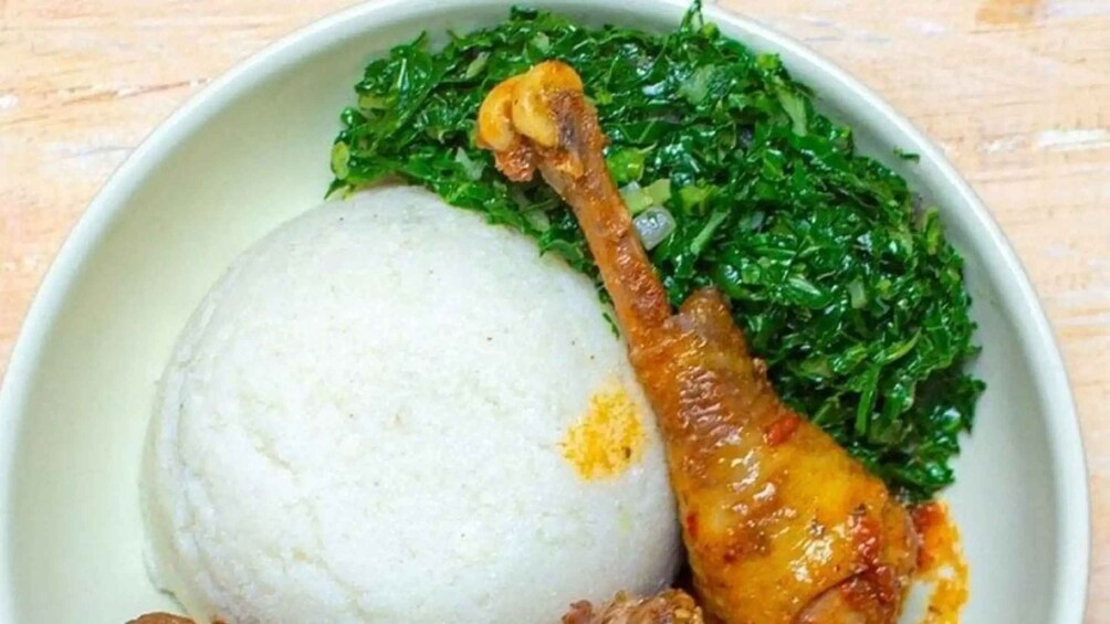 A bowl of food with a mound of white rice, a piece of fried chicken, and a side of green leafy vegetables. 2
