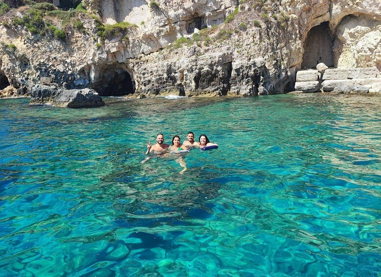 A group of people swimming in clear blue water with rocky cliffs in the background. 5
