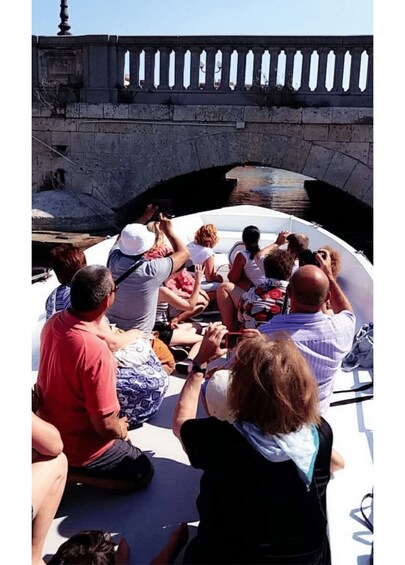 A group of people on a boat near a stone bridge. 2