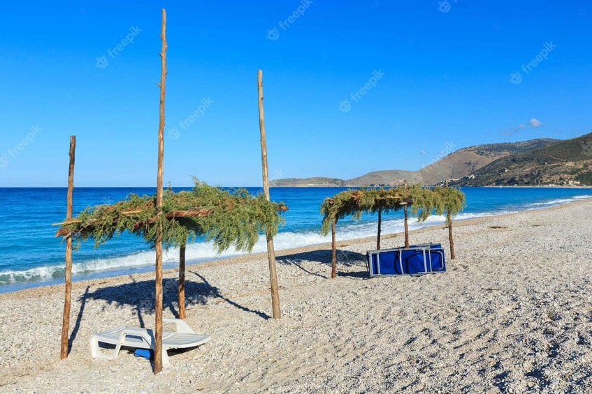 A pebbled beach with wooden structures and a blue suitcase. 2