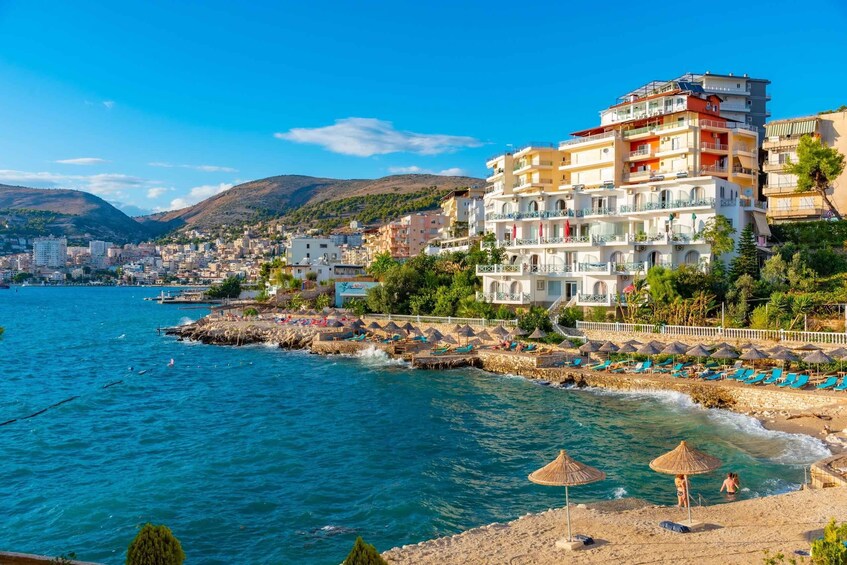 A coastal town with a beach, a pier, and a mountain in the background. 5