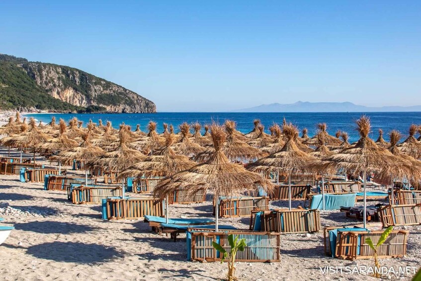A beach with rows of sunbeds and thatched umbrellas. 3