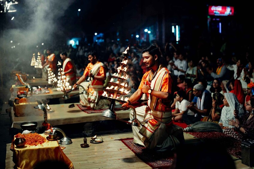A religious ceremony with participants dressed in orange and white, performing rituals with offerings and incense. 3