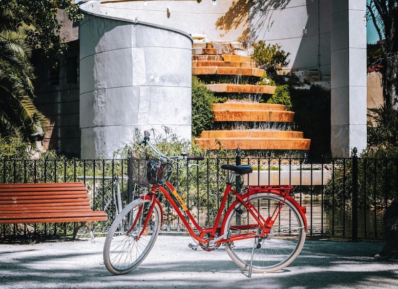 A red bicycle parked in front of a fountain with multiple tiers. 2