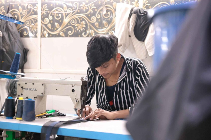 A person sewing at a machine with spools of thread and a sewing machine labeled "TYPICAL". 4