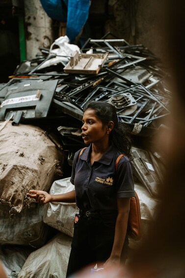 A person standing in a cluttered area with metal scraps and bags. 1