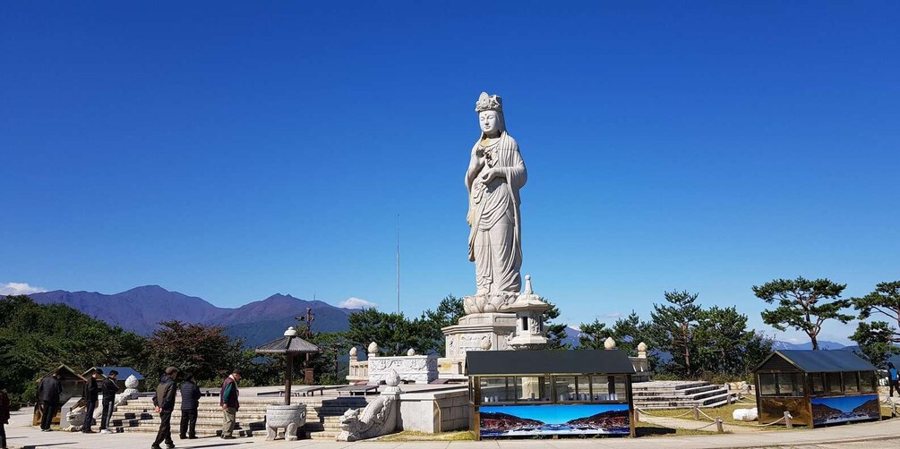 A large white statue in a park with mountains in the background. 4