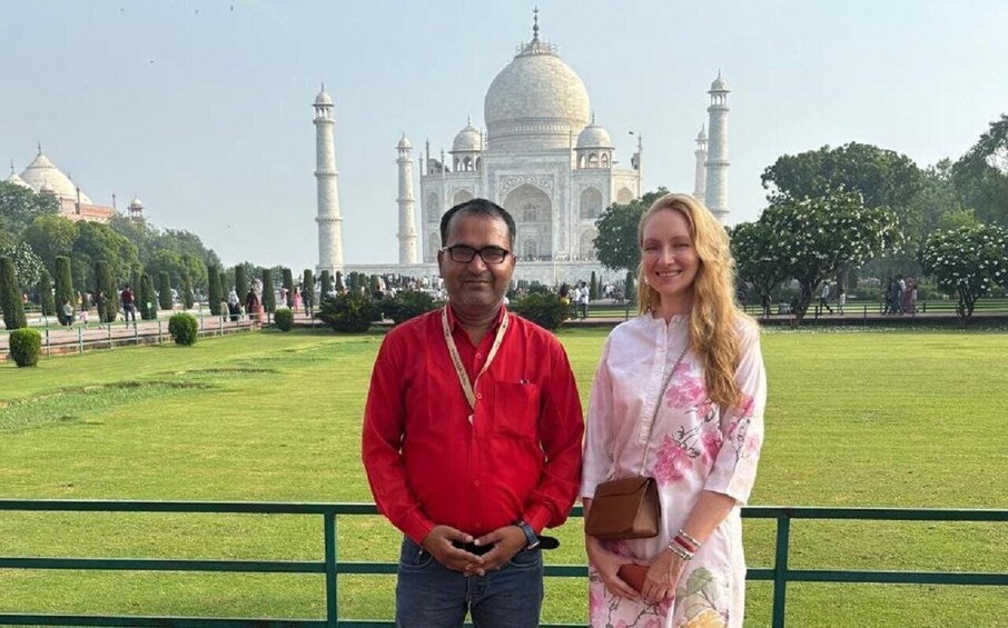 A couple standing in front of the Taj Mahal with its domes and minarets visible in the background. 1