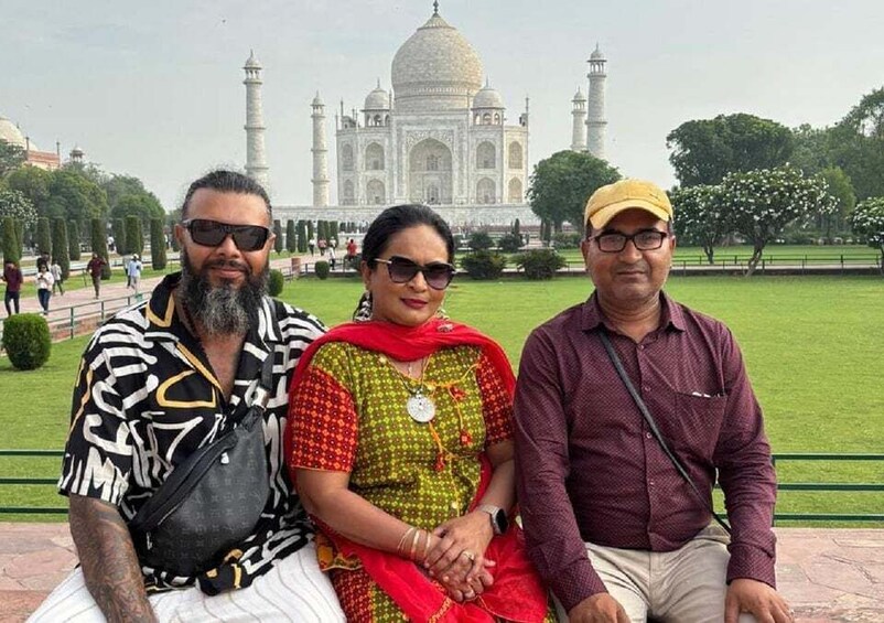 Three people sitting on a bench with the Taj Mahal in the background. 4