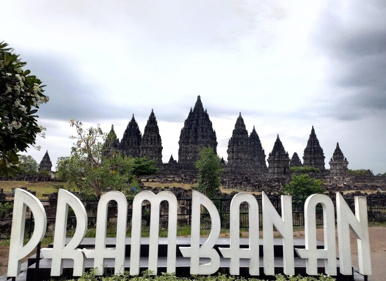 A temple complex with multiple tiered towers and a sign reading "Prambanan". 1