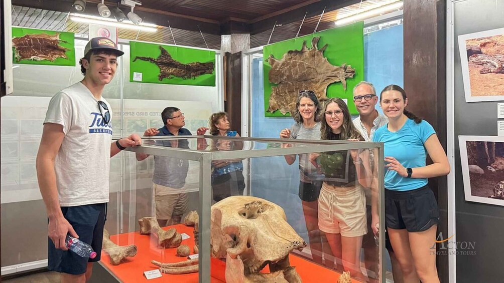 En gruppe mennesker ved en udstilling på et museum, der viser dinosaur fossiler og en stor kranie. 4