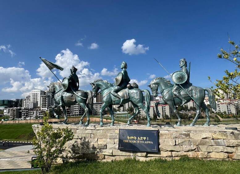 A bronze equestrian statue with inscriptions, set against a cityscape. 5