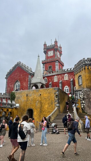A castle with a clock tower, a church with a pointed spire, and a crowd of people. 4