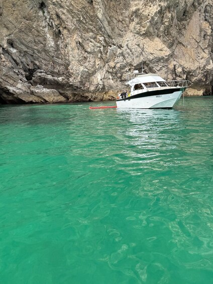 A boat named 'Argos' anchored near a rocky cliff. 1