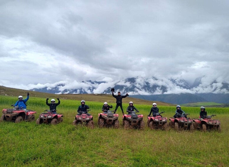 A group of people on ATVs in a grassy field with mountains in the background. 4