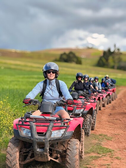A group of people riding ATVs on a dirt path in a grassy field. 2