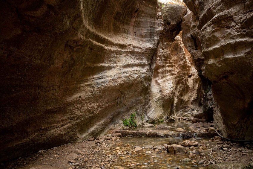 A canyon with a stream, rocky terrain, and a small waterfall. 5