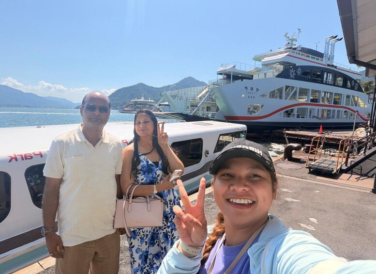 A group of people near a dock with a large white boat and a smaller boat in the background. 2