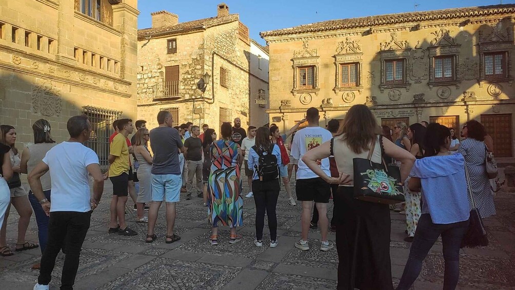 A group of people standing in a historic square with ornate buildings. 1