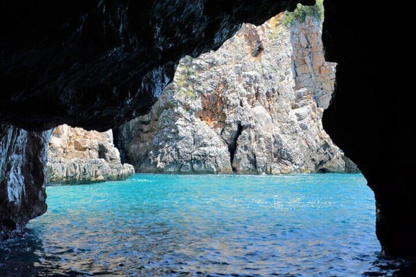 Entrada a una cueva costera con agua azul cristalina y acantilados rocosos. 3