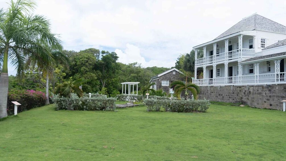 A lush garden with a white building featuring a balcony. 1