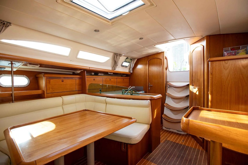 A cozy interior of a boat with a wooden table, cushioned seating, and a small window. 4