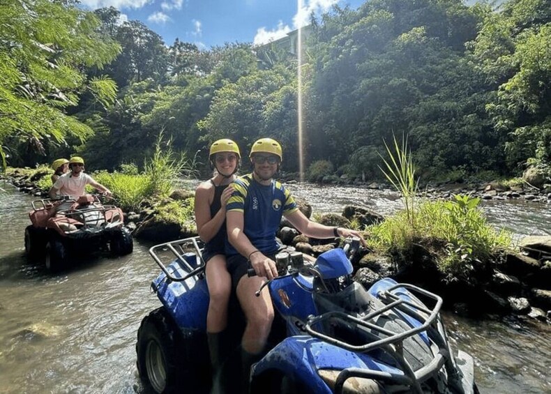 People on quad bikes in a river surrounded by greenery. 1