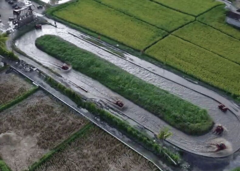 A winding road through agricultural fields with vehicles traveling on it. 4