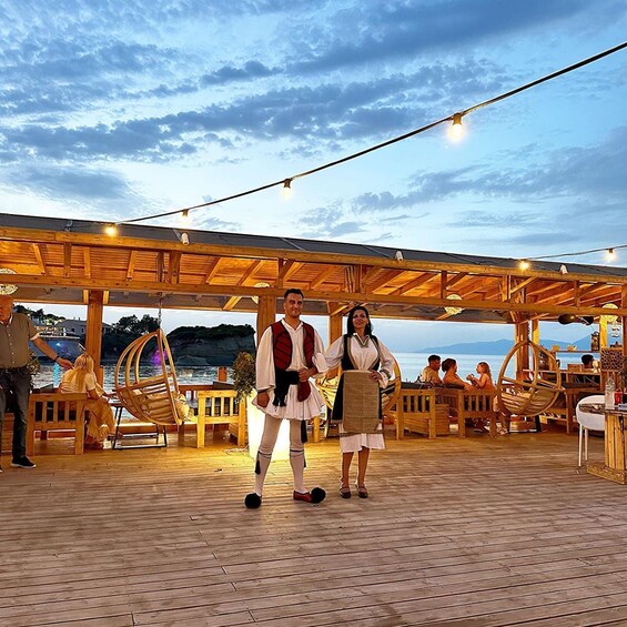 A wooden deck with hanging chairs and a wooden pergola, overlooking a body of water. 1