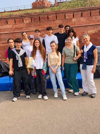 A group of people standing in front of a red brick wall with a blue platform. 2