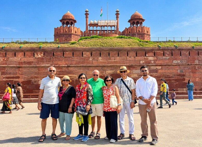 A group of people standing in front of a large red brick wall with domed structures in the background. 3