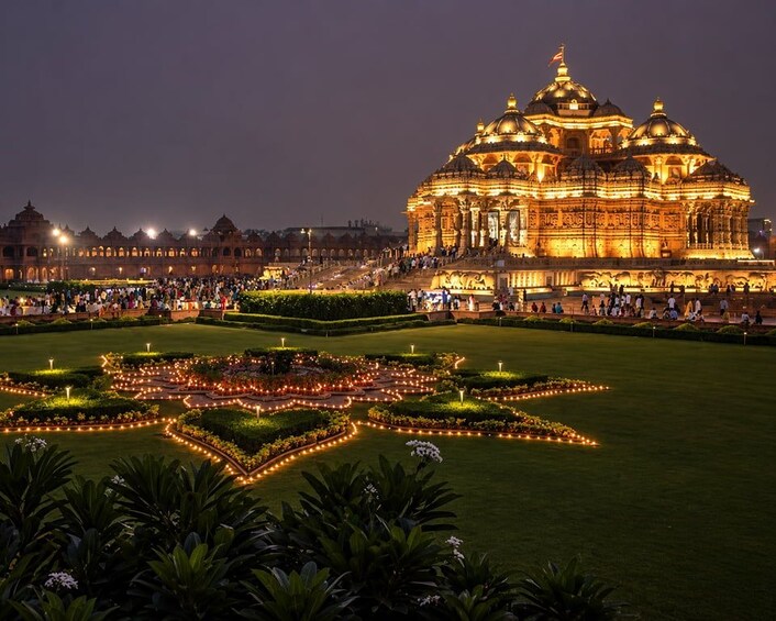 A grand illuminated building with domes, surrounded by a star-shaped garden at night. 1