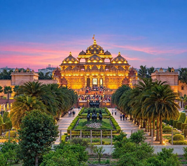 A grand temple with multiple domes, a central statue, and a well-maintained garden with palm trees. 1