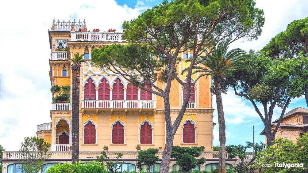 A historic building with ornate architecture, including arched windows and balconies, surrounded by lush greenery. 2