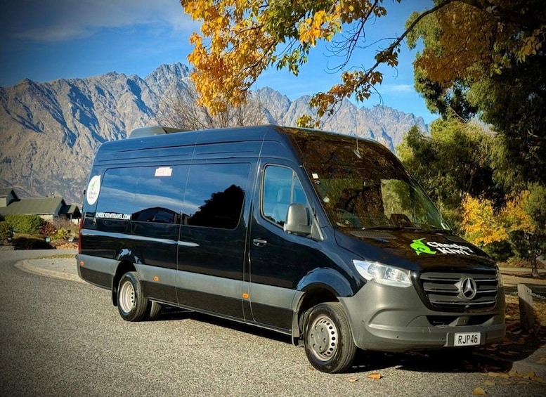 A black Mercedes van parked on a road with autumn trees and mountains in the background. 2